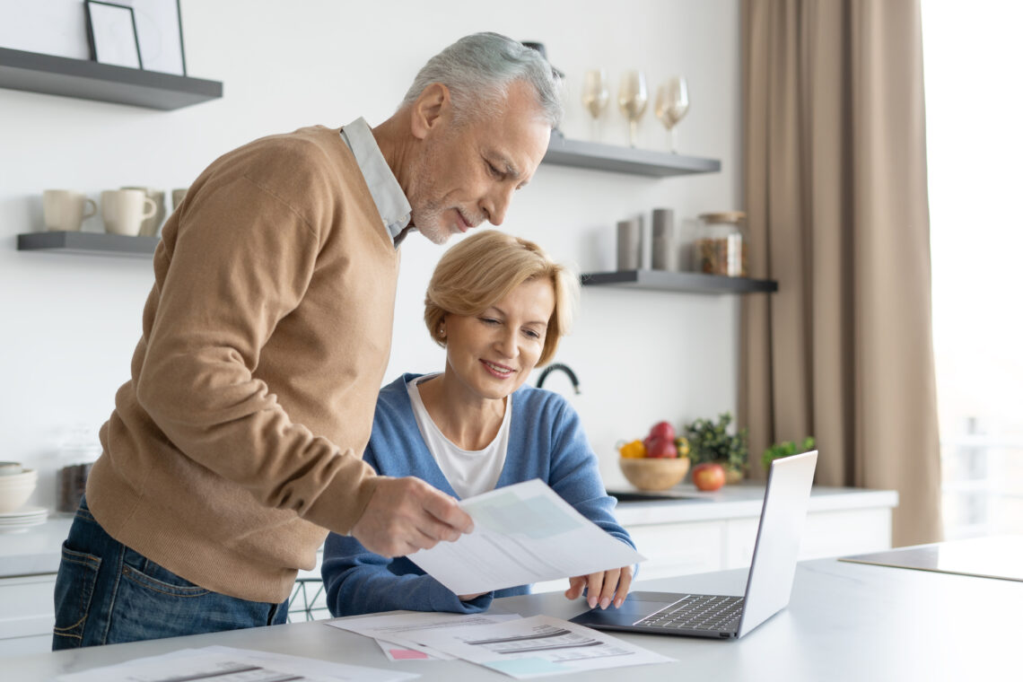 man and woman looking at paper with laptop