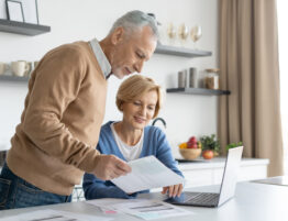 man and woman looking at paper with laptop
